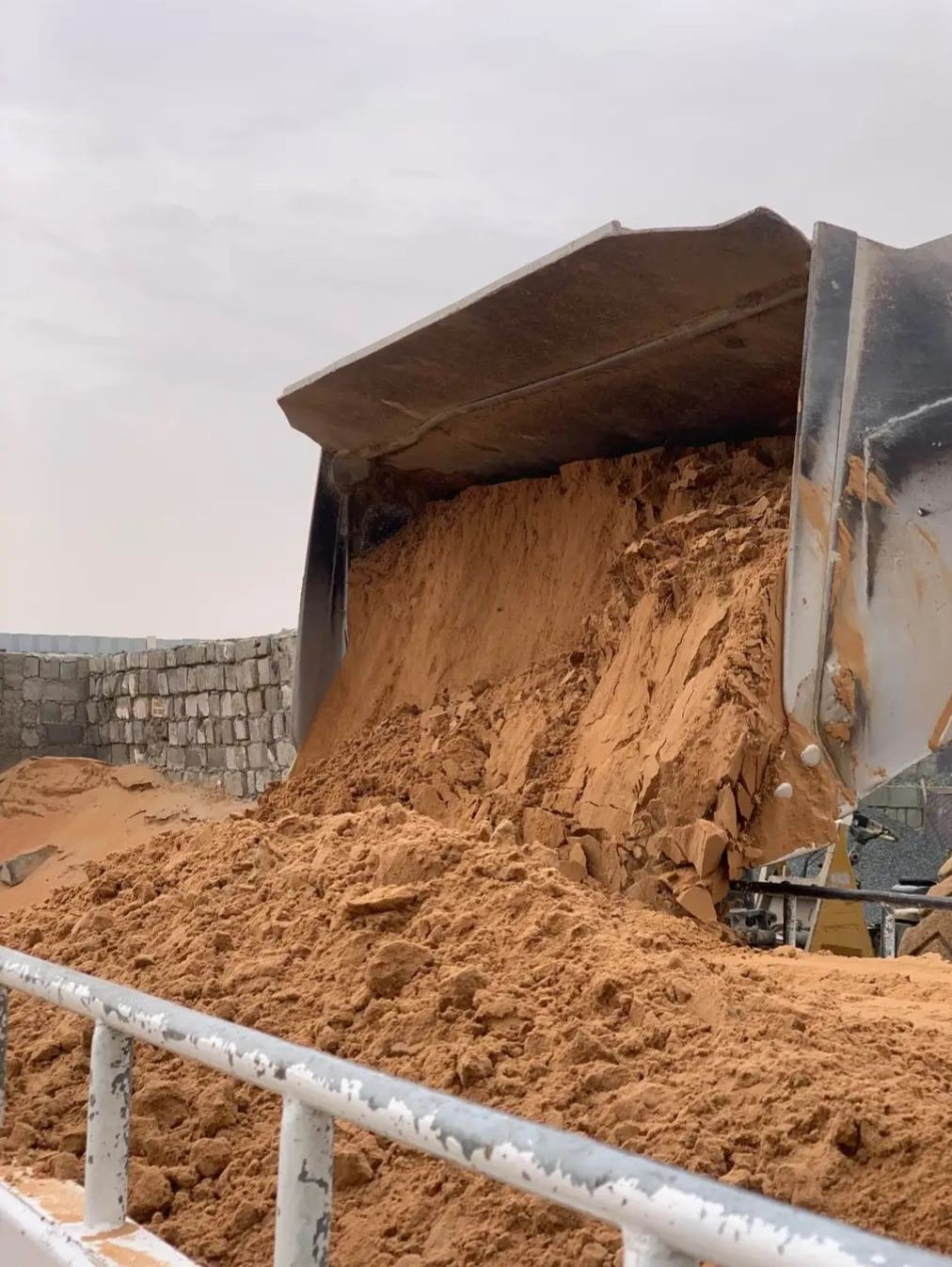 Loader tipping red sand